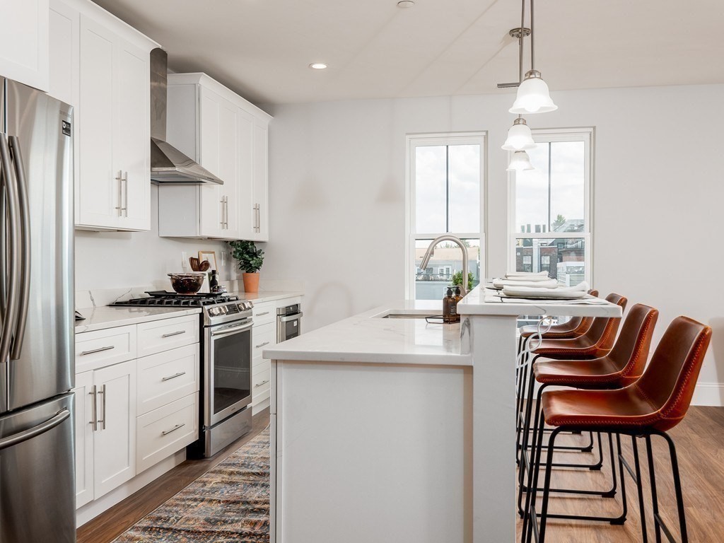 45 L Street, Unit 20 Boston, MA 02127 - Photo 8 of 28 a kitchen with stainless steel appliances granite countertop a stove a sink a microwave a refrigerator and white cabinets with wooden floors