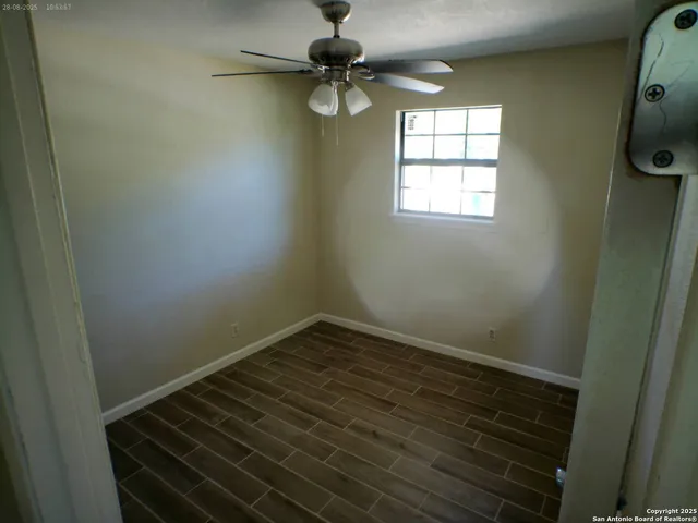 an empty room with windows and fan