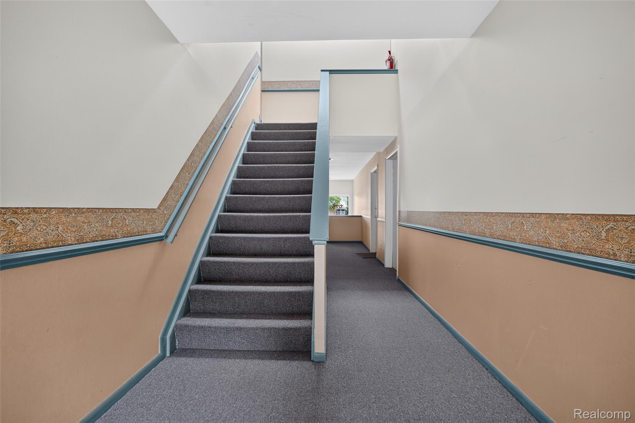 1225 Derby Road, Unit 3 Birmingham, MI 48009 - Photo 2 of 19 Carpeted staircase and hallway with a built-in wall railing