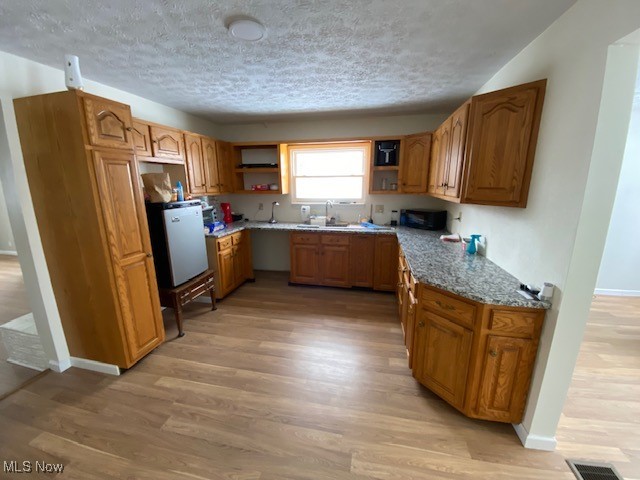 1027 Bantam Ridge Road Steubenville, OH 43953 - Photo 4 of 18 Kitchen with sink, light hardwood / wood-style flooring, a textured ceiling, and light stone countertops