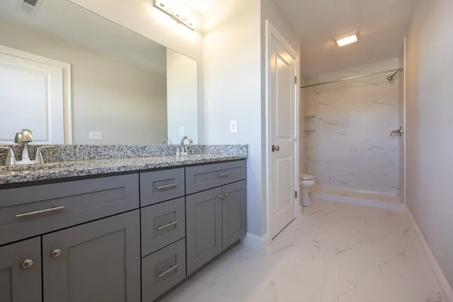 a bathroom with a granite countertop sink two mirror and a shower