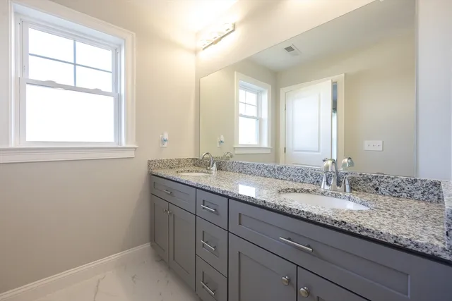 a bathroom with a granite countertop sink and a large mirror