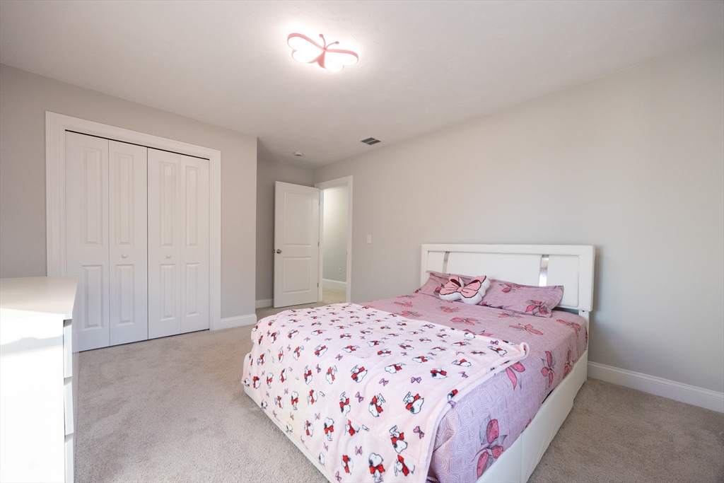 1 Clover Drive Bellingham, MA 02019 - Photo 24 of 34 a bedroom with a large bed and a chandelier