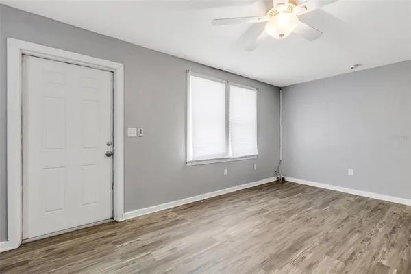 a view of an empty room with wooden floor and a window