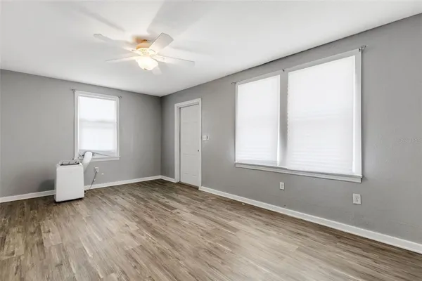 a view of an empty room with wooden floor and a window