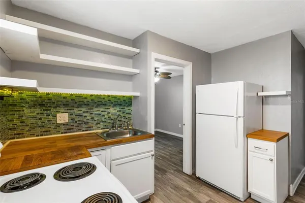 a view of a kitchen with a refrigerator and a wooden floor