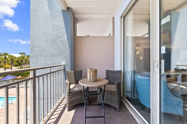 a balcony with chairs and a potted plant on a table