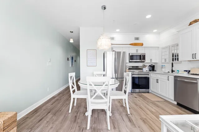 a kitchen with stainless steel appliances kitchen island granite countertop a wooden floor and white cabinets