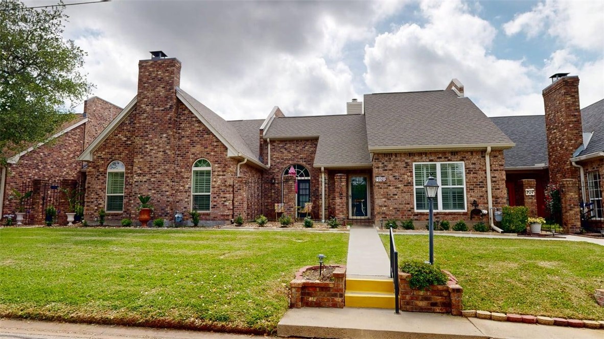 a front view of a house with garden and trees