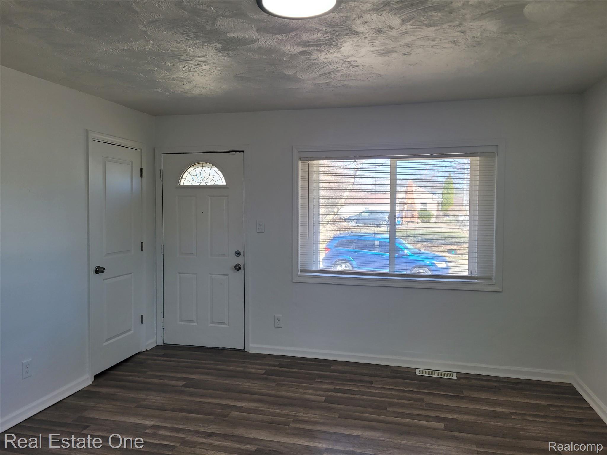 77 West Rutgers Avenue Pontiac, MI 48340 - Photo 4 of 12 Entryway featuring dark wood-style floors, plenty of natural light, and a textured ceiling