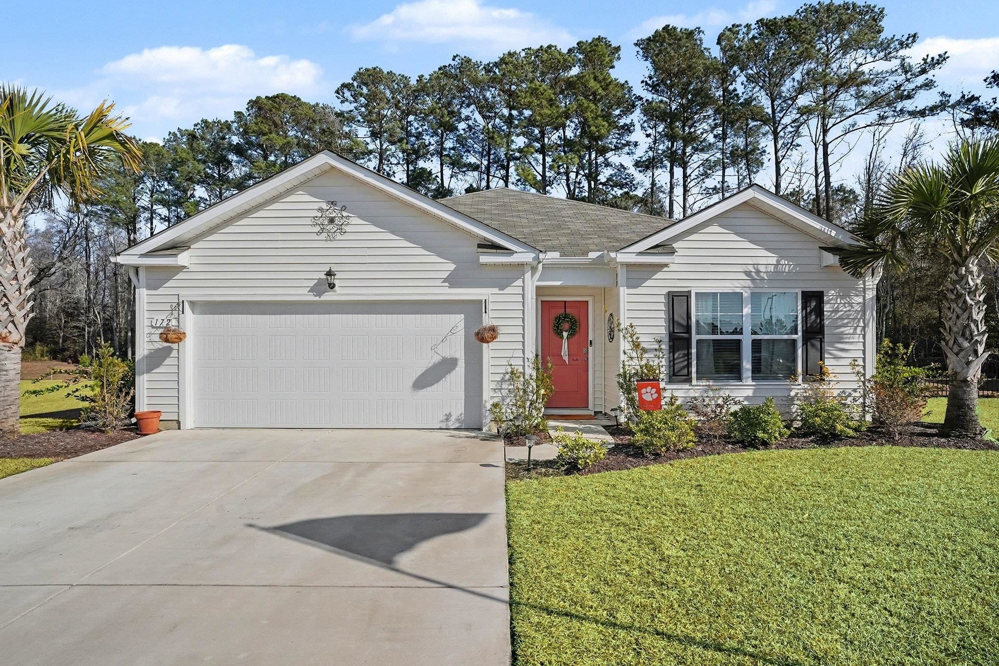 Ranch-style house featuring a front yard, concrete driveway, roof with shingles, and a garage