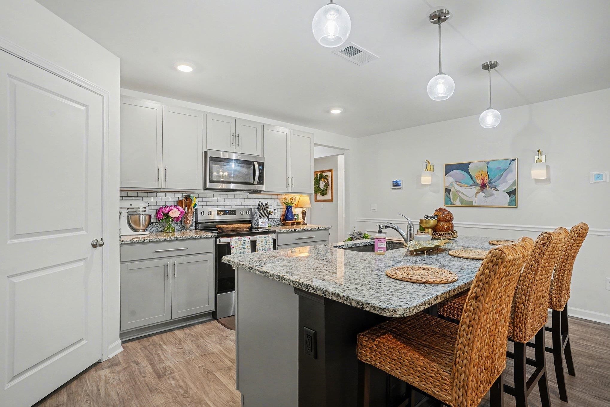 172 Seasons Trace Loop Longs, SC 29568 - Photo 13 of 37 Kitchen featuring stainless steel appliances, light wood-type flooring, a breakfast bar area, light stone countertops, and an island with sink