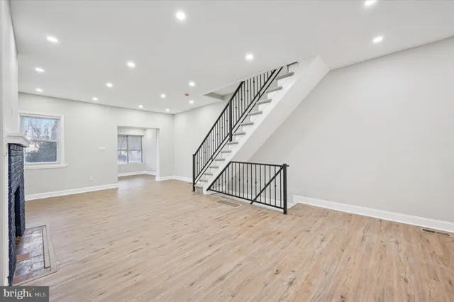 a view of an empty room with wooden floor and stairs