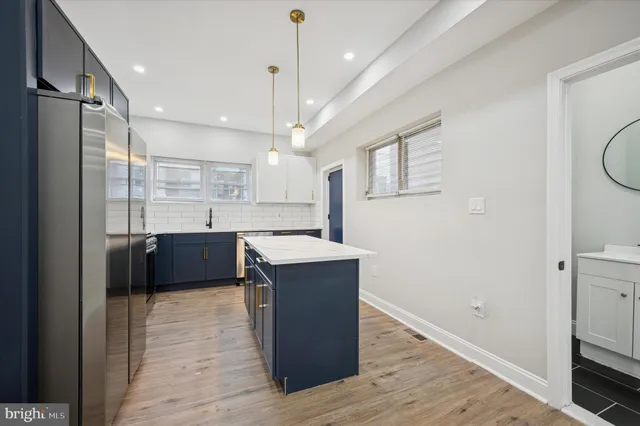 a kitchen with kitchen island a counter top space a sink stainless steel appliances and cabinets