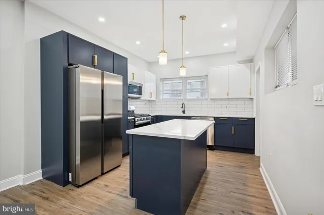 a kitchen with stainless steel appliances granite countertop a refrigerator a sink a stove and a wooden floors