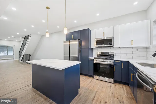 a kitchen with stainless steel appliances kitchen island a stove a sink a refrigerator and cabinets