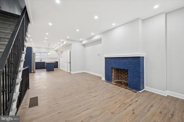 a view of kitchen and empty room with wooden floor