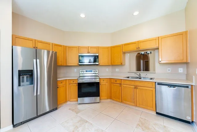 a kitchen with stainless steel appliances granite countertop a refrigerator a sink dishwasher stove and oven