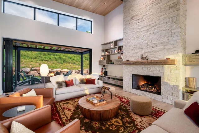 a living room with furniture a fireplace and a floor to ceiling window