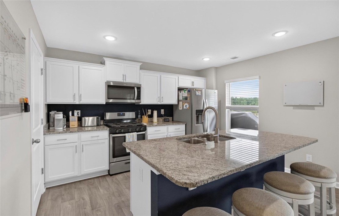 213 Millhone Way Pendleton, SC 29670 - Photo 5 of 25 A well-appointed kitchen features ample white cabinetry and granite countertops, complemented by stainless steel appliances and an inviting island with seating.