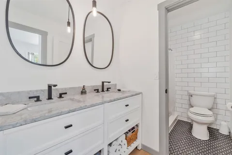 a bathroom with a granite countertop toilet a sink and a mirror