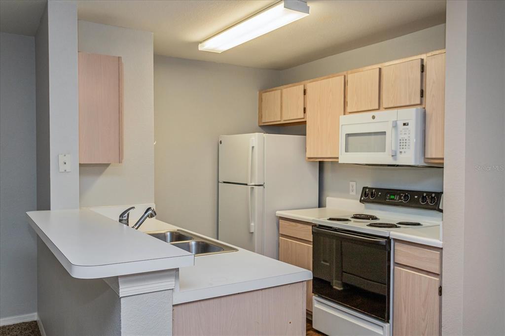5455 Vineland Road, Unit 3214 Orlando, FL 32811 - Photo 6 of 25 a kitchen with a sink a stove and refrigerator