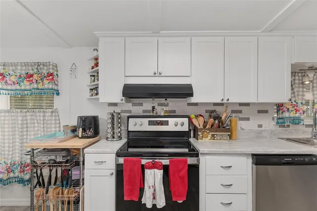 a kitchen with stainless steel appliances a refrigerator a sink dishwasher a dining table and chairs with wooden floor