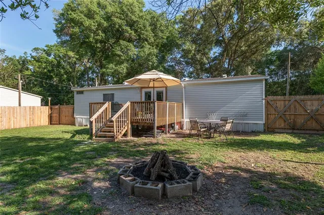 a view of a wooden house with a small yard and wooden fence