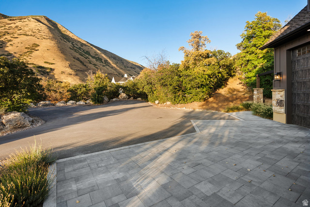 1141 South Oak Leaf Lane Springville, UT 84663 - Photo 17 of 147 Paver driveway with an integrated asphalt approach, bordered by mature landscaping and a stone-clad pillar with an exterior sconce