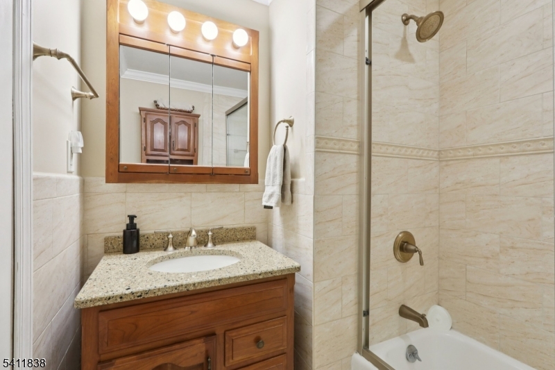4 Southview Road Randolph, NJ 07869 - Photo 18 of 30 a bathroom with a granite countertop sink a mirror a bathtub and shower