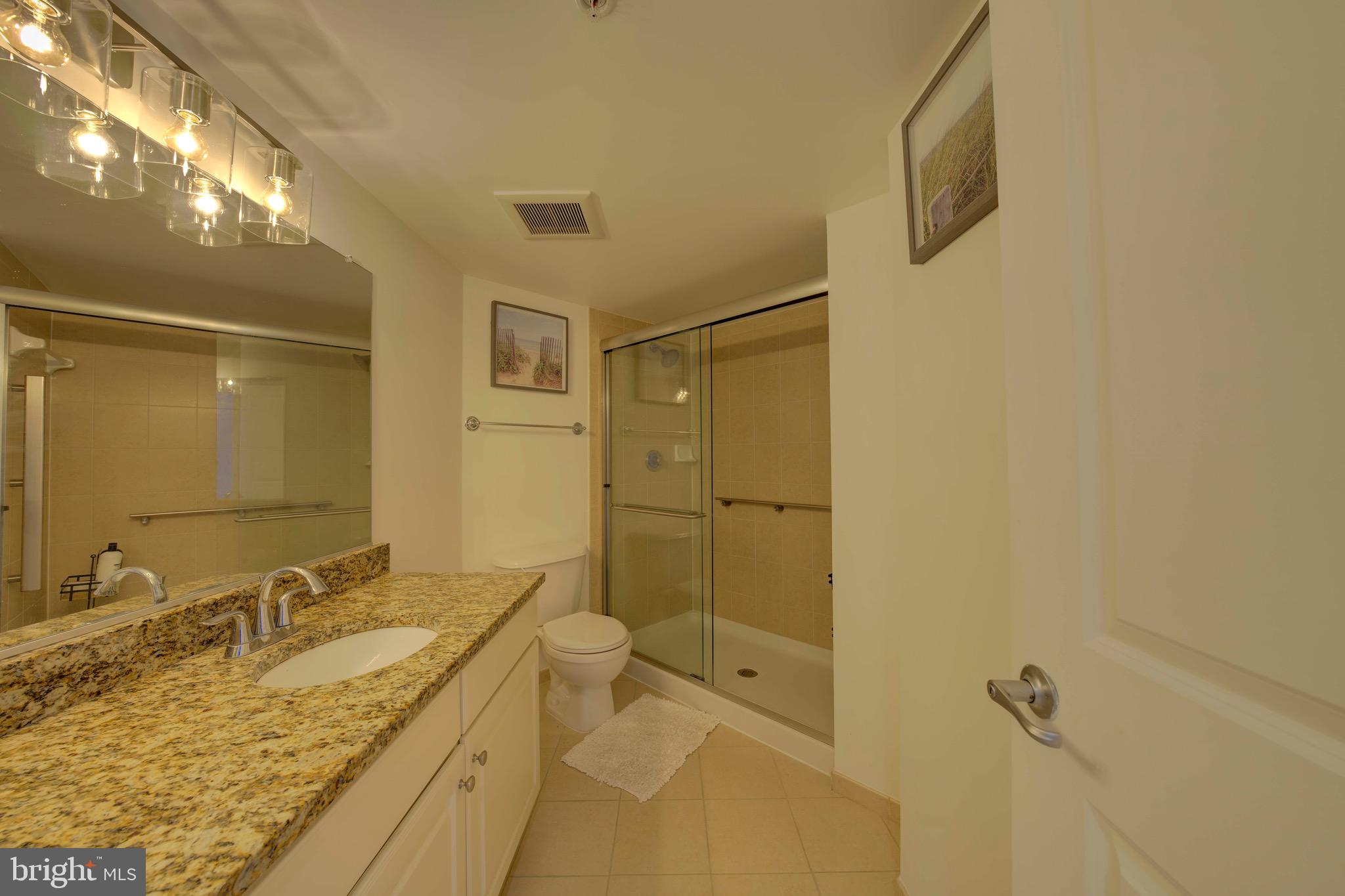11800 Sunset Hills Road, Unit 222 Reston, VA 20190 - Photo 31 of 70 a bathroom with a granite countertop sink a mirror and shower