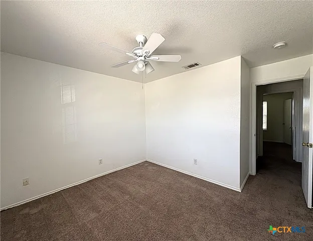an empty room with a ceiling fan and a window