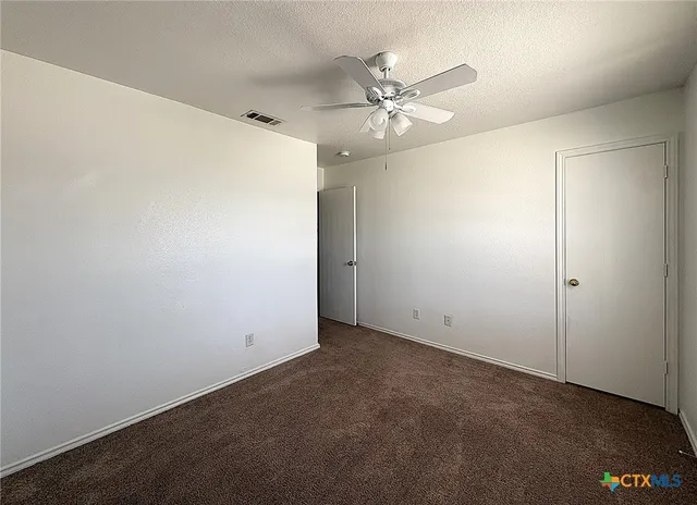 an empty room with a chandelier fan and closet area