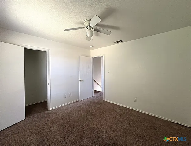 an empty room with a ceiling fan and a window