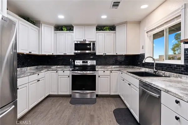 a kitchen with stainless steel appliances granite countertop a stove a sink and a microwave