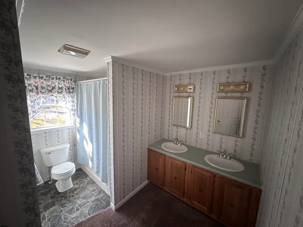 a bathroom with a granite countertop sink a toilet a mirror and shower