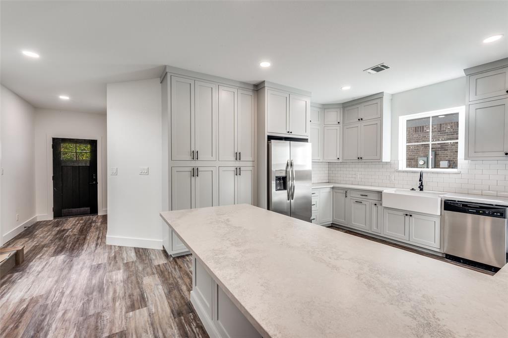 1013 Murphy Street Gainesville, TX 76240 - Photo 4 of 22 a large kitchen with a refrigerator a sink dishwasher a stove and white cabinets with wooden floor