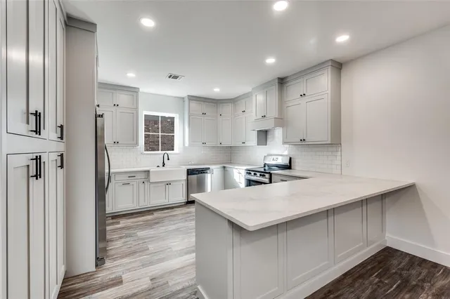 a kitchen with white cabinets a sink stove and refrigerator