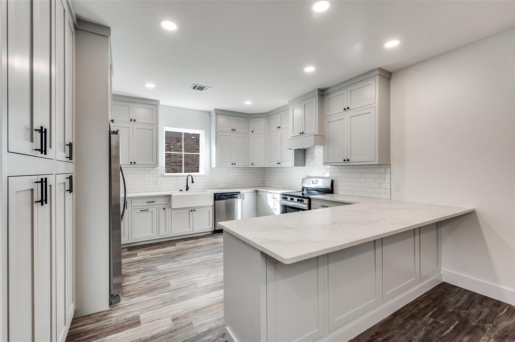 1013 Murphy Street Gainesville, TX 76240 - Photo 7 of 22 a kitchen with white cabinets a sink stove and refrigerator