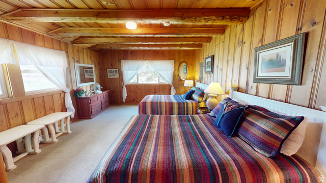 315 Abbey Road Moab, UT 84532 - Photo 5 of 46 Bedroom featuring a wood ceiling with exposed beams, carpet, and wooden walls