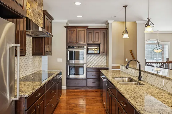 a kitchen with stainless steel appliances granite countertop a sink a stove and a wooden floors