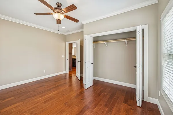 an empty room with wooden floor chandelier fan and windows
