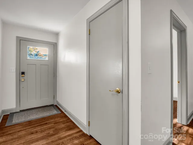 a view of a hallway with wooden floor and a bathroom