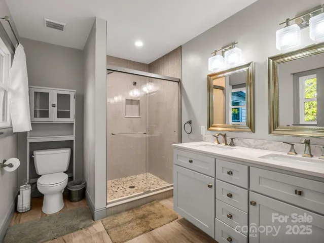 a bathroom with a double vanity sink toilet mirror and bathtub
