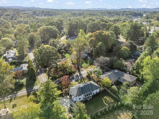 an aerial view of residential houses with outdoor space and trees