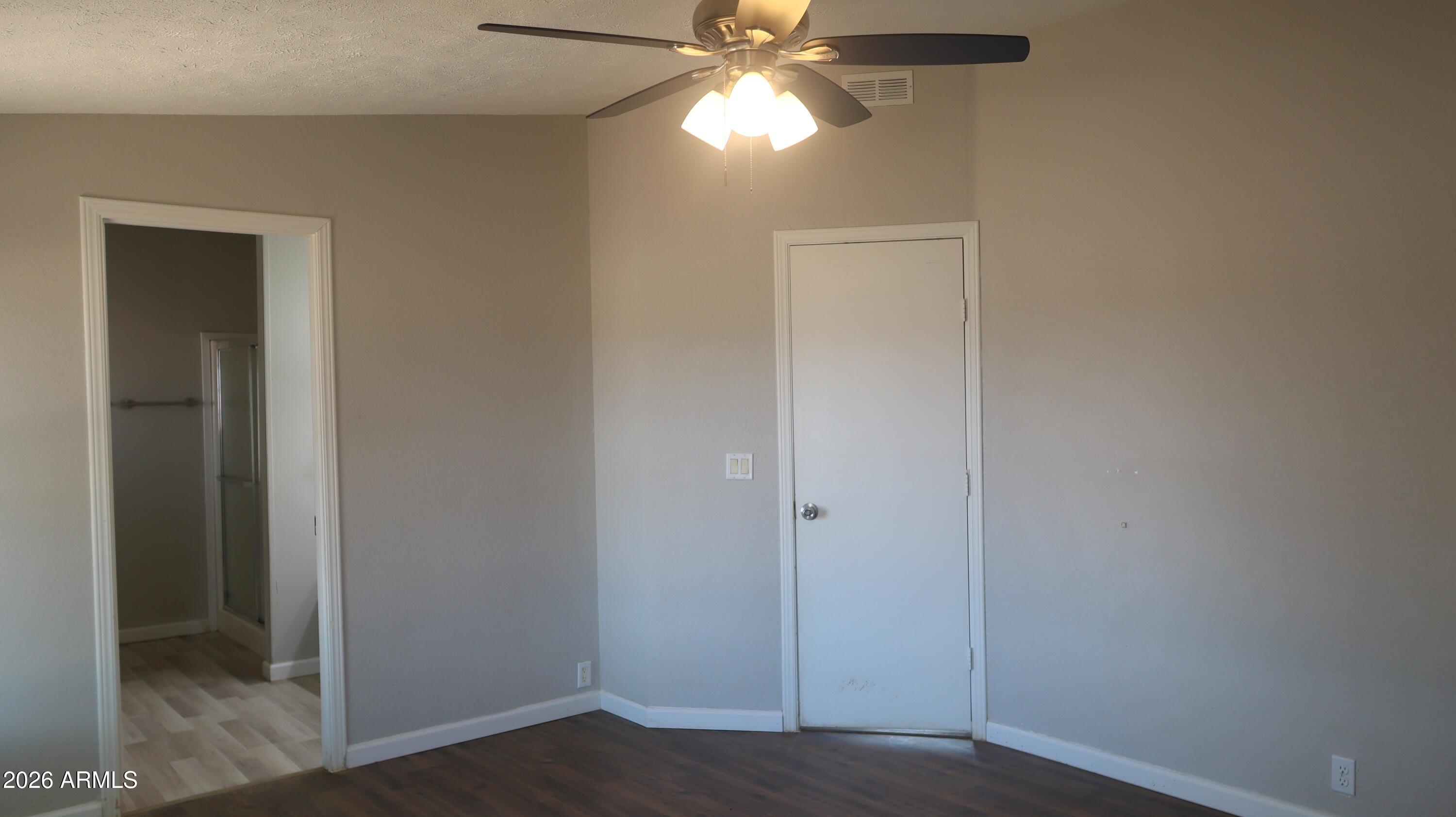 20163 North Sage Street Maricopa, AZ 85139 - Photo 14 of 54 a view of an empty room with wooden floor and a ceiling fan