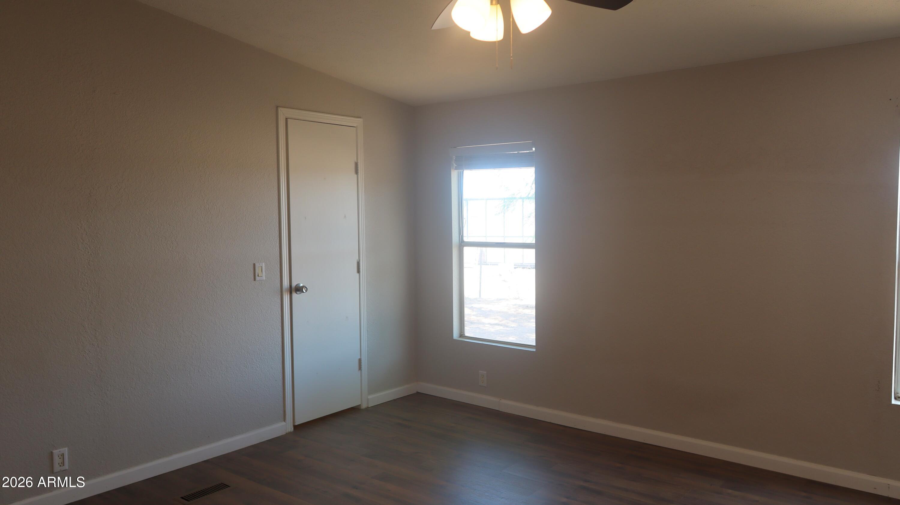 20163 North Sage Street Maricopa, AZ 85139 - Photo 15 of 54 an empty room with a window and wooden floor