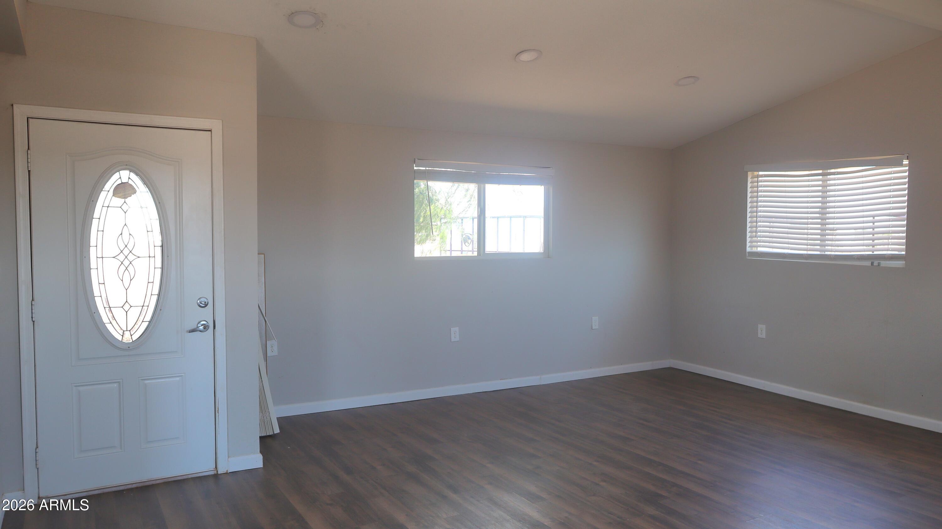 20163 North Sage Street Maricopa, AZ 85139 - Photo 27 of 54 an empty room with wooden floor a clock and a window
