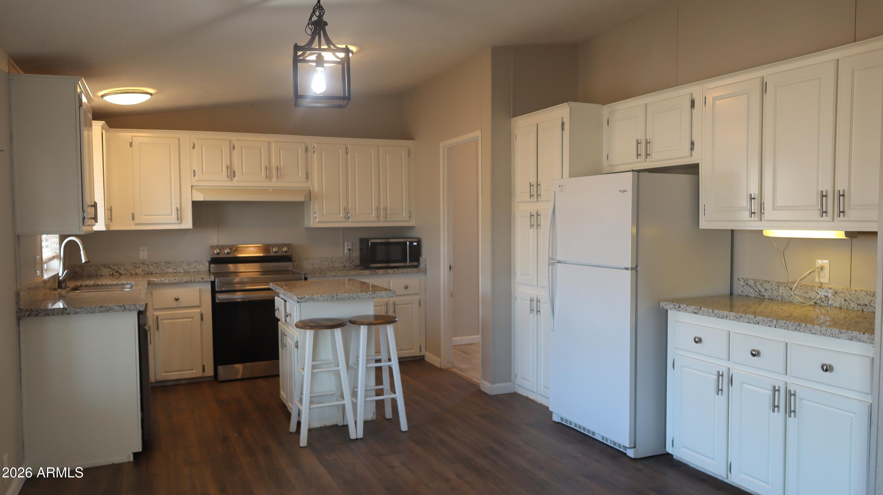 20163 North Sage Street Maricopa, AZ 85139 - Photo 5 of 54 a kitchen with granite countertop a refrigerator a sink dishwasher a stove and white cabinets with wooden floor