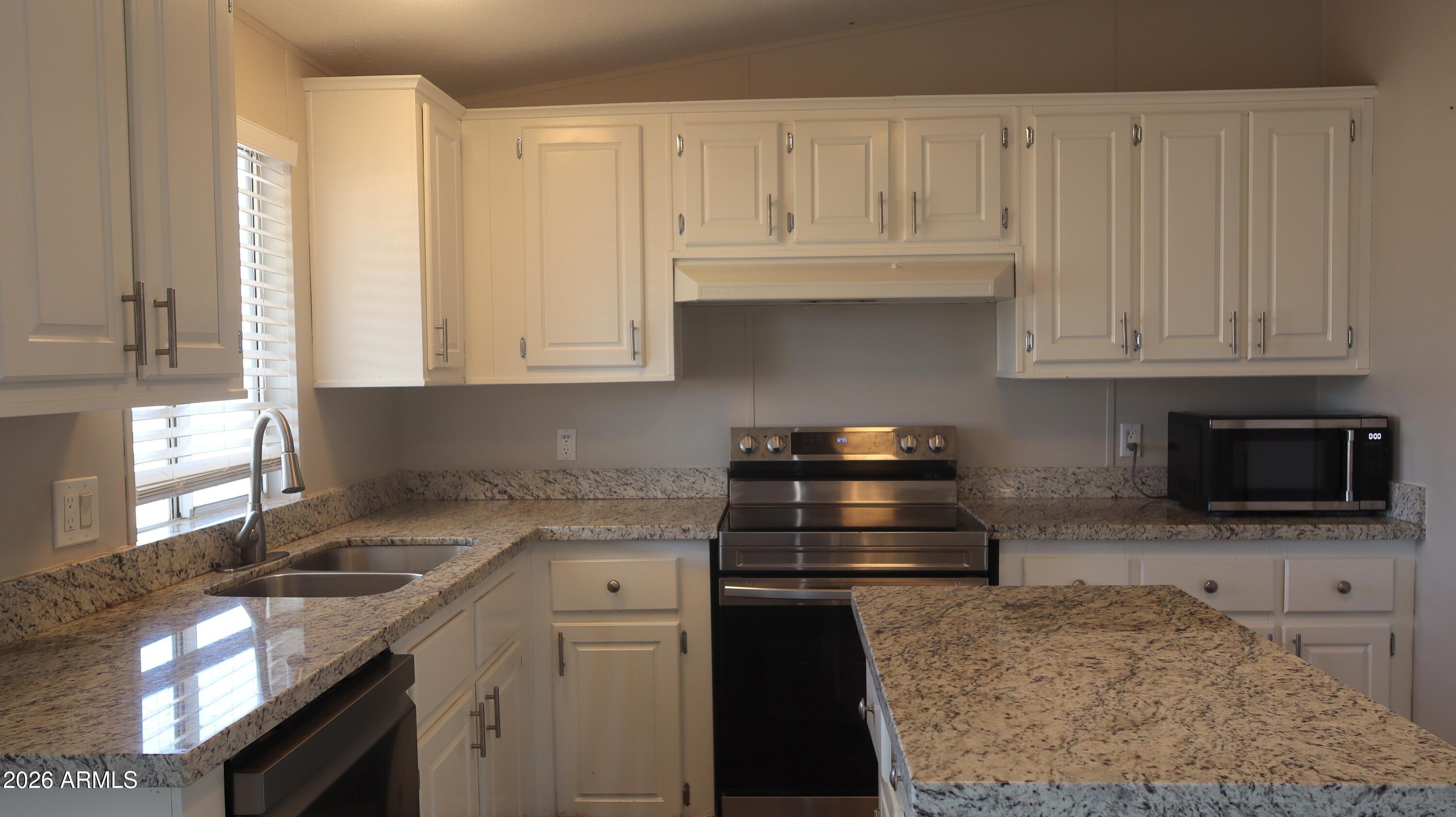 20163 North Sage Street Maricopa, AZ 85139 - Photo 6 of 54 a kitchen with granite countertop a stove a sink and a granite counter tops